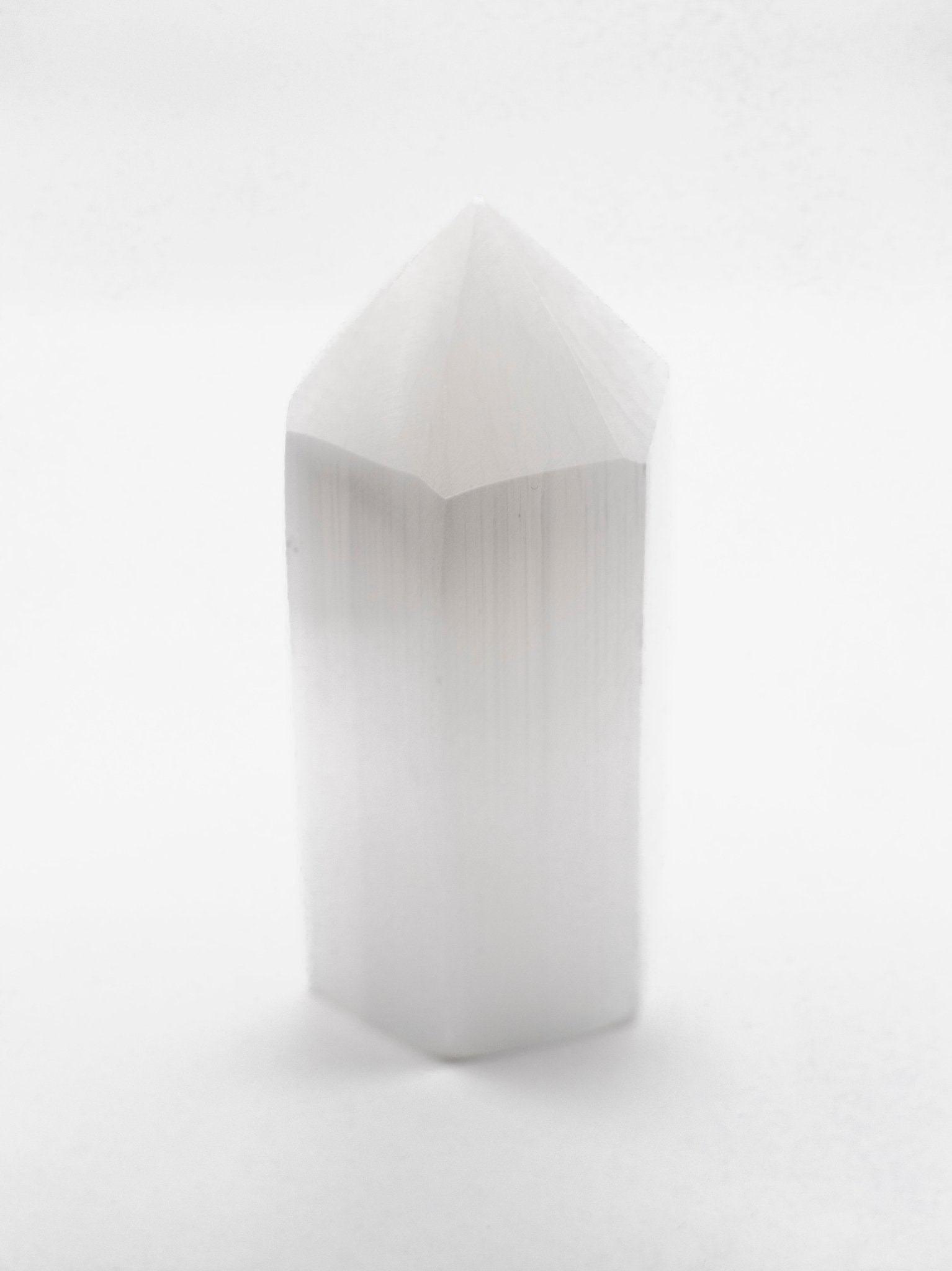 Geschliffene Selenit Spitze vor weißem Hintergrund