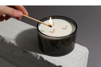 Hochwertige Duftkerze im schlichten Glas wird mit einem Streichholz angezündet – Symbolbild für natürliche Inhaltsstoffe und bewusste Kerzenwahl